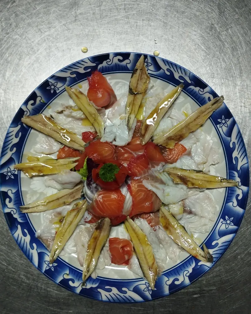 Marinated anchovies and fish arranged on a blue-rimmed plate