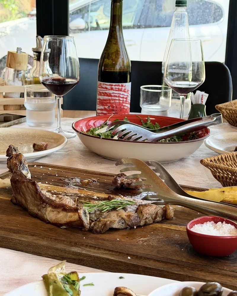 Grilled meat on a wooden board with salad and red wine