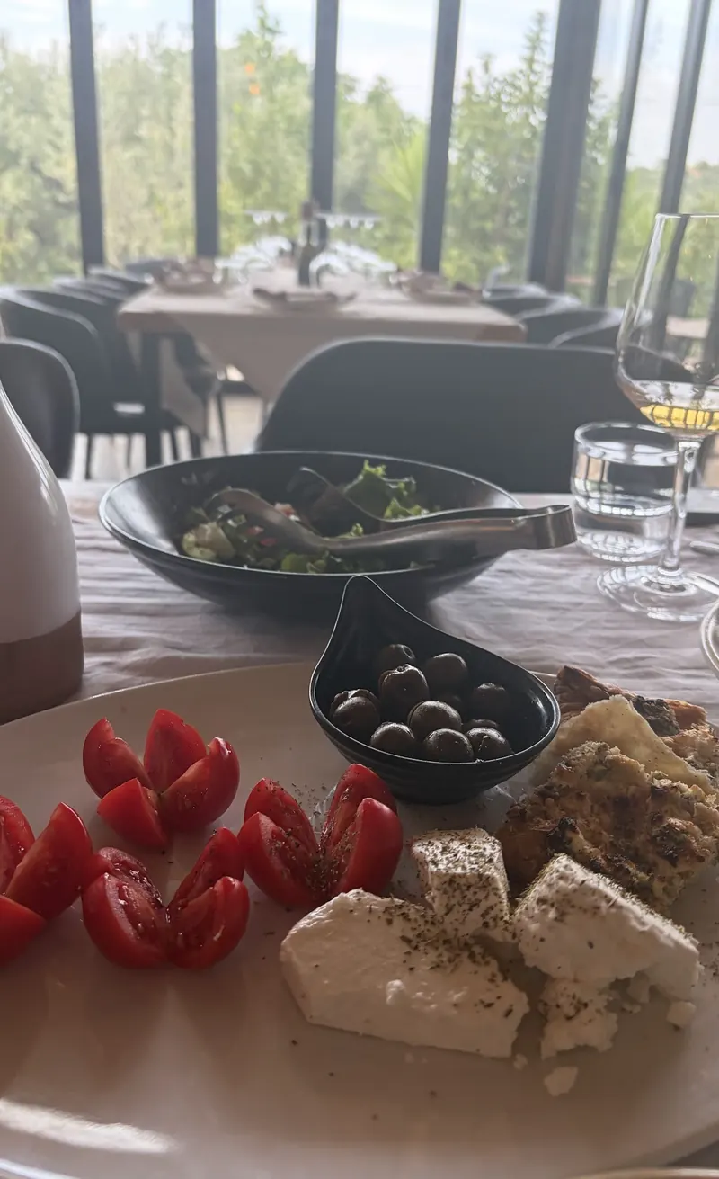 Tomatoes, white cheese, olives and a salad by the window