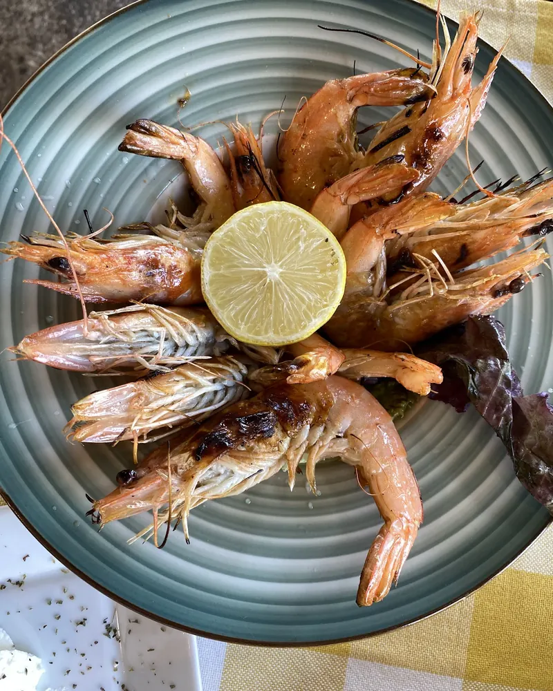 Grilled prawns around half a lemon on a green plate
